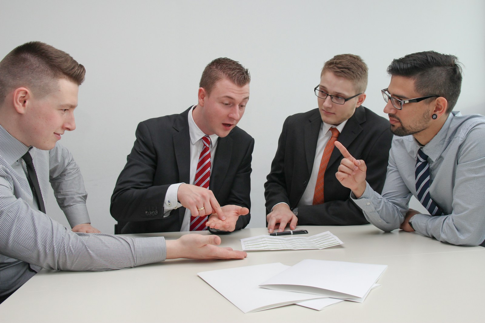 four men sitting at desk talking, BOP